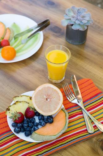 a table with two plates of fruit and orange juice at Santiago Resort - Palm Springs Premier Gay Men’s Resort in Palm Springs