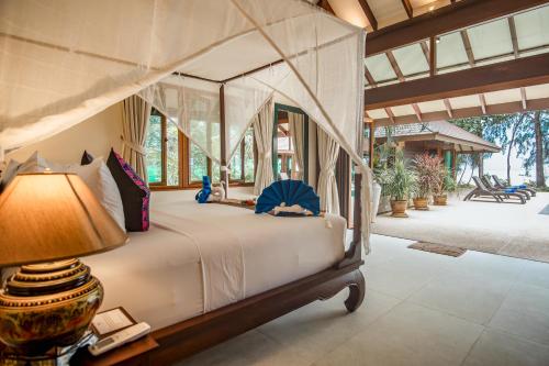 a bedroom with a canopy bed with a lamp at Koh Jum Beach Villas "A member of Secret Retreats" in Ko Jum
