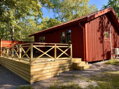 a red cabin with a wooden deck in front of it at Bergs Gård & Hållsvikens Gård in Västerljung