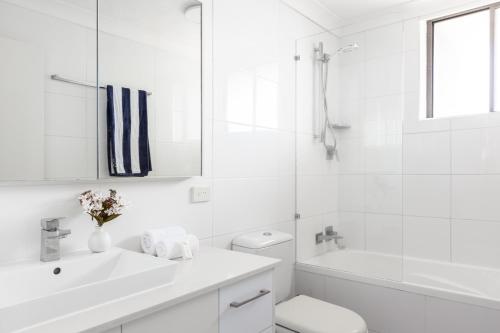 a white bathroom with a sink and a toilet at Columbia Beachfront Apartments on Rainbow Bay in Gold Coast