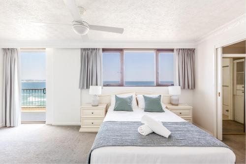 a bedroom with a bed with blue and white pillows at Columbia Beachfront Apartments on Rainbow Bay in Gold Coast