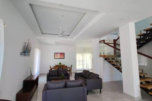 a living room with two couches and a staircase at Sunset Bay Beach Villa in Mangalore