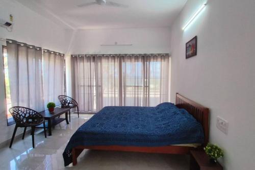 a bedroom with a bed and a table with chairs at Sunset Bay Beach Villa in Mangalore