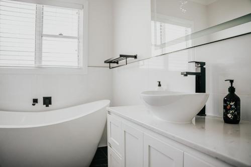 une salle de bain blanche avec une baignoire et un lavabo dans l'établissement Cow Bell Cottage, à Trentham