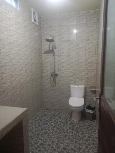 a bathroom with a toilet and a shower at Me'Sari Guest House in Karangasem
