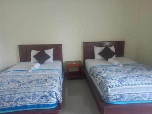 two beds sitting next to each other in a room at Me'Sari Guest House in Karangasem