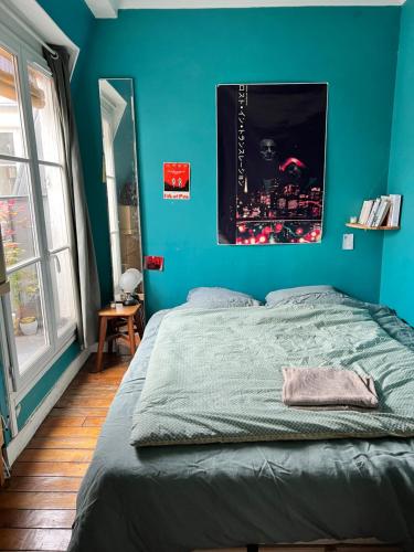 - une chambre bleue avec un lit et un mur bleu dans l'établissement Charmant T2 parisien avec balcon, à Paris