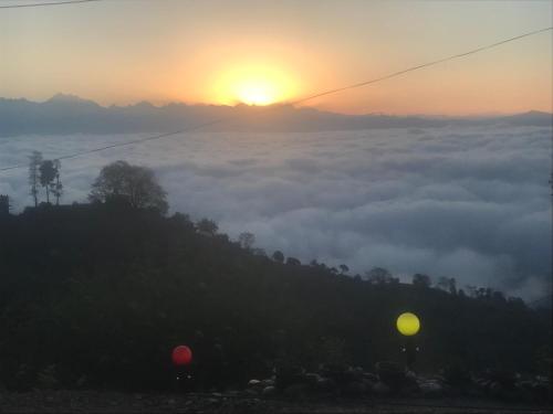 a view of the sun rising over a fog covered hill with two balloons at Sunrise Point Homestay in Nagarkot