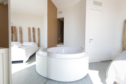 a bathroom with a white tub in a room with two beds at Palas Cerequio in La Morra