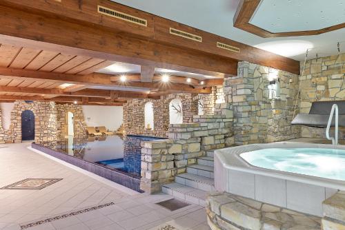 a large bathroom with a stone wall and a hot tub at Aktiv & Spa Hotel Alpenrose in Schruns-Tschagguns