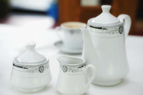 a group of white vases and cups on a table at Sashini Homestay in Sigiriya
