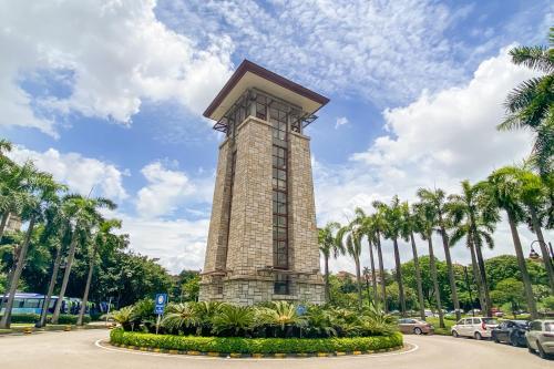 a clock tower in a park with palm trees at Guangzhou He She Art Apartment in Guangzhou