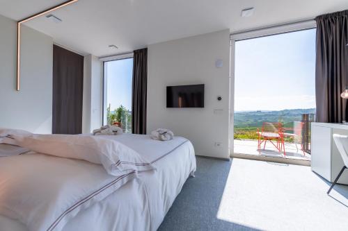 a white bedroom with a bed and a large window at Palas Cerequio in La Morra