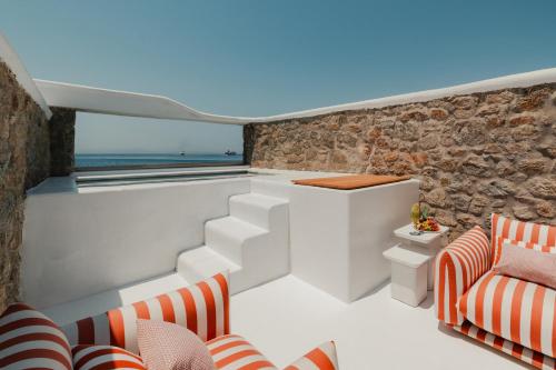 a balcony with white furniture and a stone wall at Croco Mykonos in Tourlos