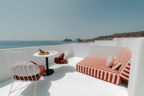 a balcony with a table and chairs and the ocean at Croco Mykonos in Tourlos