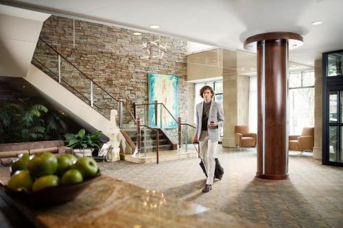 a woman walking through a room with a staircase at Metterra Hotel on Whyte in Edmonton