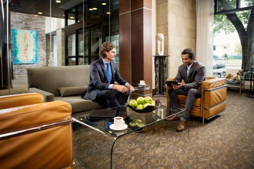 two men in suits sitting in a lobby at Metterra Hotel on Whyte in Edmonton
