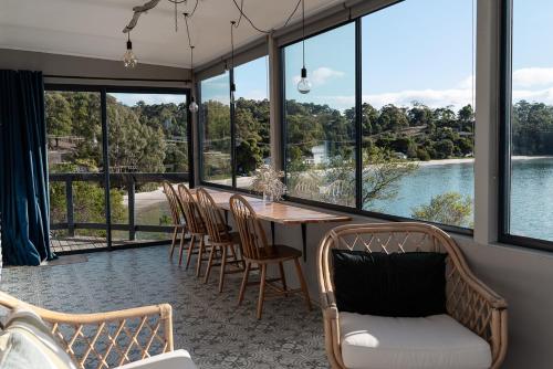 a dining room with a table and chairs and windows at Surveyor's Cottage in Surveyors Bay