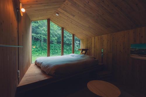 a bed in a wooden room with a window at Earthboat Hakuba in Hakuba