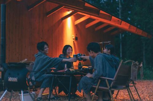 a group of people sitting at a table with a woman at Earthboat Hakuba in Hakuba