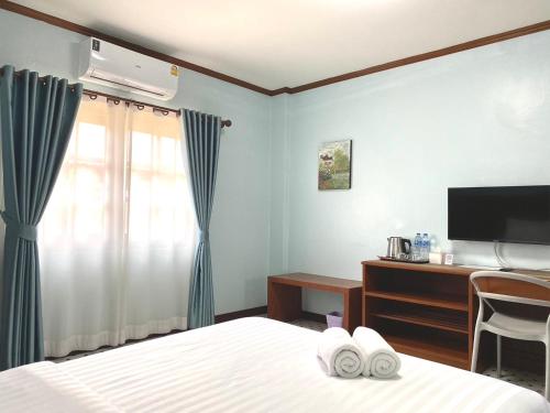 a bedroom with a bed and a desk and a television at Chainatgrand Hotel in Ban Khung Mae Luk On
