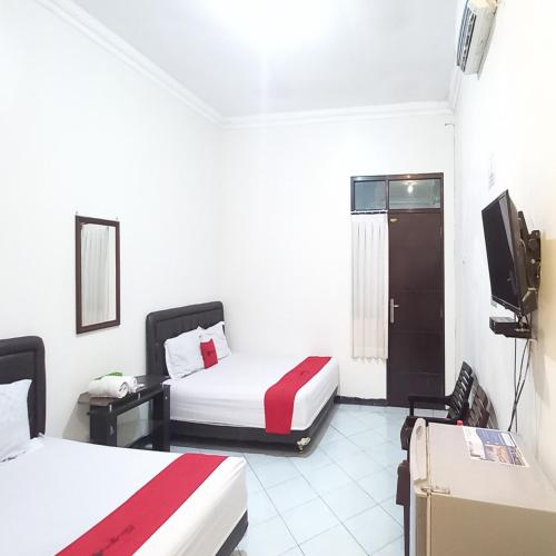 a hotel room with two beds and a television at RedDoorz Syariah at Hotel Pandan Wangi near Alun Alun Sidoarjo in Sidoarjo