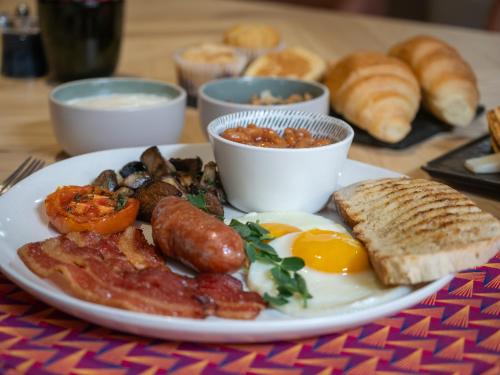 a plate of breakfast food with eggs sausage and bread at AtholPlace Hotel & Villa in Johannesburg