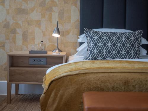a bed with a pillow and a nightstand with a lamp at AtholPlace Hotel & Villa in Johannesburg
