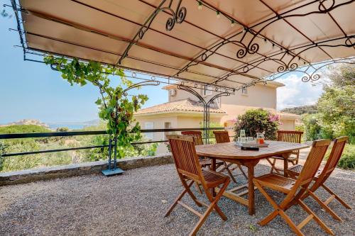 une table et des chaises en bois sous une pergola dans l'établissement Villa Hestia Calvi - Maison avec piscine, à Calvi