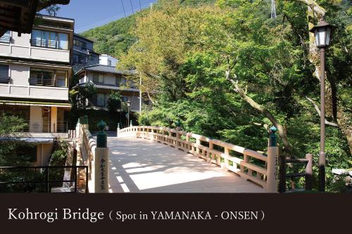 a wooden bridge over a road in a city at Yamanaka Onsen Kagari Kisshotei in Kaga