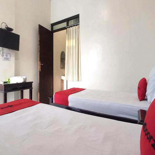a hotel room with two beds and a window at RedDoorz Syariah at Hotel Pandan Wangi near Alun Alun Sidoarjo in Sidoarjo