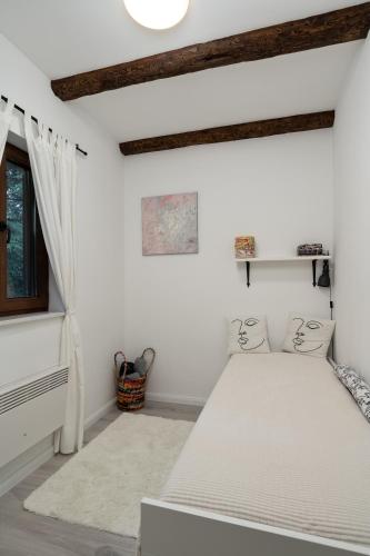 a white bedroom with a bed and a window at Holiday House Tjaša in Lokve