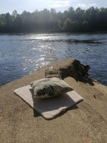a pillow on a towel on the shore of a river at Vikendica Drinski mir in Loznica