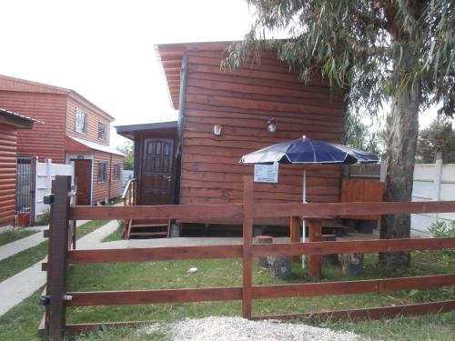 a wooden house with an umbrella next to a fence at Cabañas Estrellas Doradas in Miramar