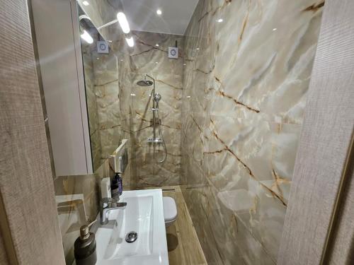 Un baño con lavabo y pared de mármol. en Agora luxury Studio 4, en Loutraki