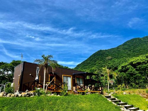a small house with a hill in the background at HoshinoHana ~ Beach house~ in Ishigaki Island
