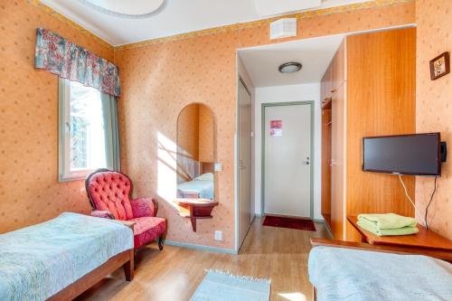 a bedroom with a bed and a tv and a chair at Boutique Hotelli Kivennapa in Pieksä
