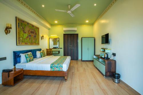 a bedroom with a bed and a television in it at The Marwar Hotel & Gardens in Jodhpur