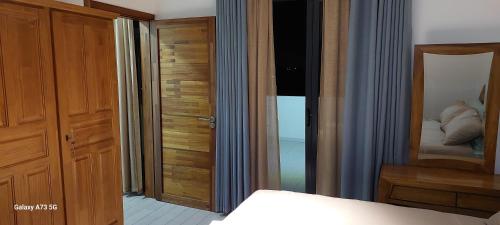 a bedroom with a wooden door and a mirror at Villa Chehara Bed n Breakfast in Grand Baie