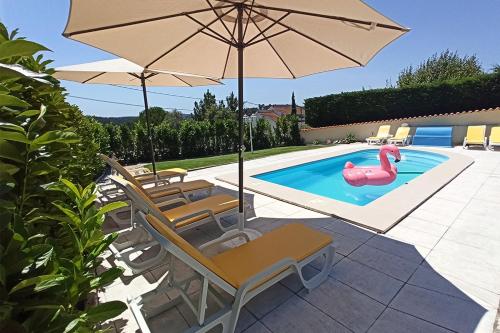 a pool with an umbrella and chairs and a pink flamingo at Refúgio de Alburitel in Alburitel