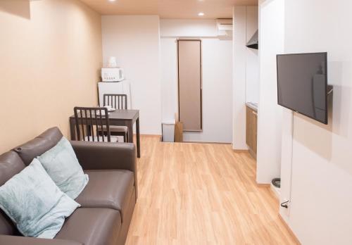 a living room with a couch and a table at Tycq Nagahashi TYレジデンス in Osaka
