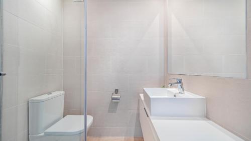 a white bathroom with a toilet and a sink at Paraiso Pueblo Pools Gym Views in Benahavís