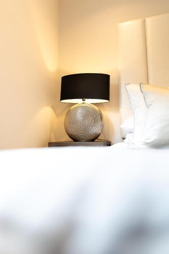 a lamp sitting on a bed in a bedroom at Exclusive Cardiff City Centre Apartment in Cardiff