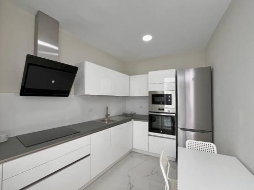 プエルト・デ・ラ・クルスにあるHouse Patio Azul Puerto de la Cruzの白いキャビネットとステンレス製の冷蔵庫を備えたキッチン