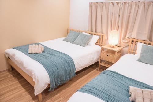 a bedroom with two beds and a lamp on a table at Tycq Nagahashi TYレジデンス in Osaka