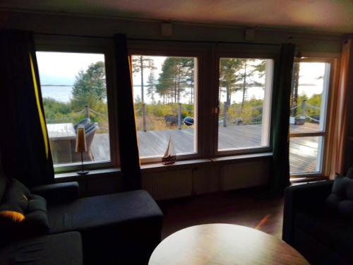 a living room with three windows and a table at Havsnära villa in Nordmaling