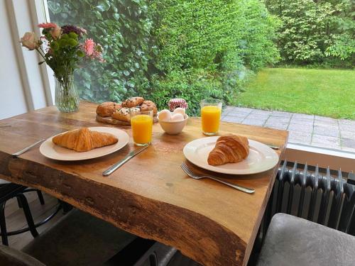 a wooden table with plates of food and glasses of orange juice at Boshuisje Koolmees park Hoefbos Otterlo in Otterlo