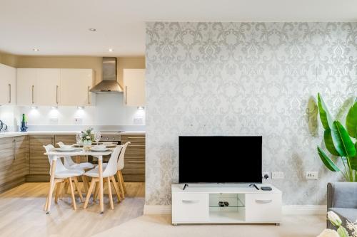 a kitchen and living room with a tv and a table at Modern Living Stevenage 2bed Apartment Town Centre up to 8 people Tesco at Doorstep in Stevenage