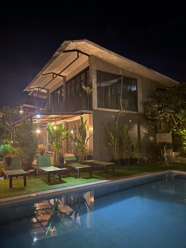 a house with a swimming pool at night at The Jungle Hostel Canggu in Canggu