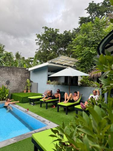 a group of people sitting on benches next to a pool at The Jungle Hostel Canggu in Canggu